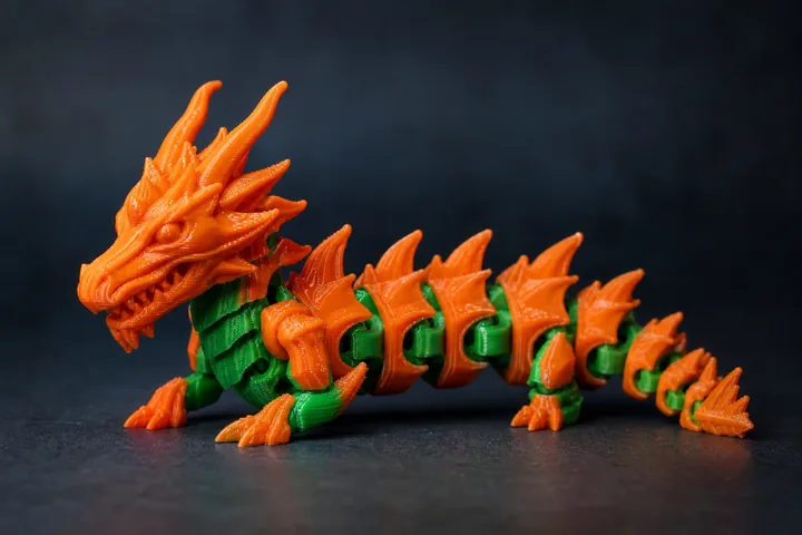 Figura articulada de dragón impresa en 3D en PLA naranja y verde